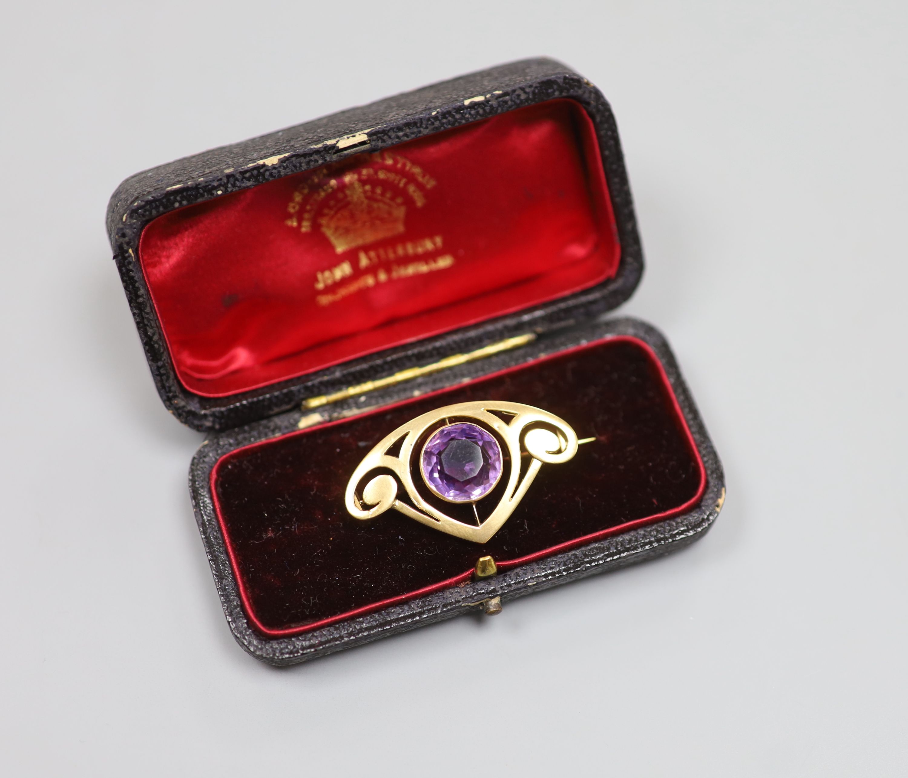 An early 20th century Art Nouveau yellow metal and amethyst set stylised brooch